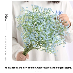 Close-up of model holding a bundle of sky blue gypsophila artificial flowers for decor
