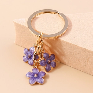 Detail of three purple enamel flower pendants on a gold-tone keyring with petal texture
