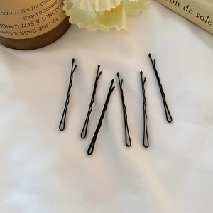 Lot de six épingles à cheveux noires ondulées sur un élégant tissu blanc froissé