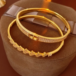 Macro view of gold-plated bangle with CD logo and pavé-set zircons on velvet box