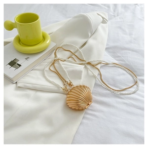 Detail of shell-shaped gold evening bag with pearl chain and metallic snake strap