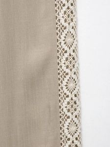 Detailed macro view of khaki linen fabric with delicate creamy white crochet lace trim