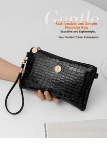 Detailed view of black crocodile embossed clutch bag with sparkling diamond emblem decoration.