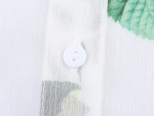 Détail macro de la texture en mousseline blanche avec bouton rond et imprimé floral