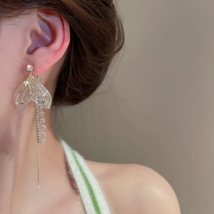 Eleganti orecchini a pendente con catene dorate, fiocchi in resina e cristalli lucenti