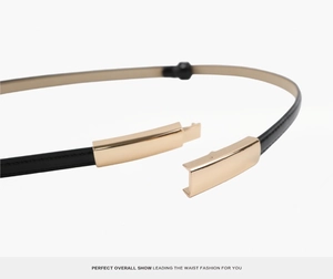 Close-up of black leather slim belt with sleek gold metal buckle for women's dresses