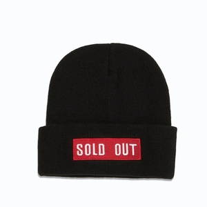 Detailed texture of black knit beanie featuring red rectangular SOLD OUT embroidery patch