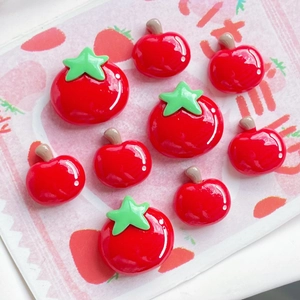 Close-up of glossy red resin tomato and apple charms for DIY phone case crafts
