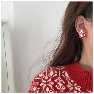 Close-up of a festive red Christmas bell earring with white snowflake details on a model