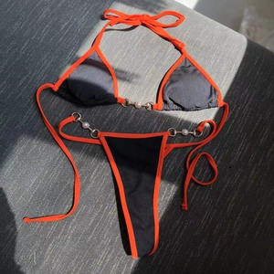 Close-up of black ribbed bikini with orange trim and elegant pearl bead accents
