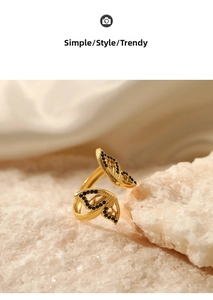 Close-up of golden butterfly ring with black zircons on white stone and satin background