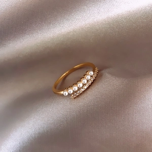 Detailed shot of double-layered gold ring with pearls and pavé diamonds on silk