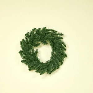 Lush green artificial Christmas wreath with dense pine needle textures on a warm background