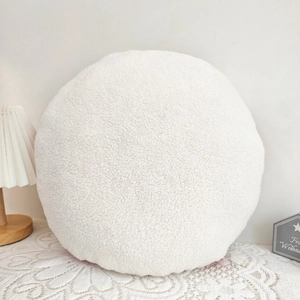 Close-up of a white sherpa fleece round pillow with cozy texture for Christmas decor