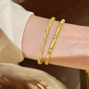 Detail of gold money bag bracelet and twisted bangle set with sparkling star-set stones
