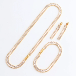 Detail of gold jewelry set featuring rectangular zircon necklace, bracelet, and earrings