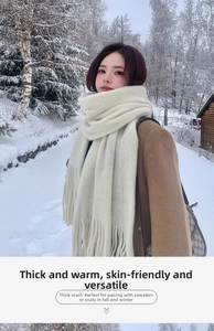 Close-up of thick cream knitted scarf with long tassels in a snowy forest winter setting