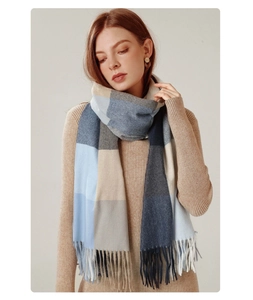 Detail of the blue and beige plaid scarf showing soft fabric texture and fringe tassels