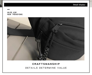 Detail view of the black crossbody bag featuring double zippers and woven pull cords