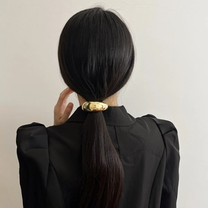 Rear view of a golden metallic arched hair ring styling a ponytail on a model