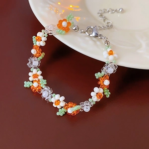 Close-up of handmade beaded floral bracelet with orange petals and silver lobster clasp
