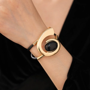 Detail of a vintage golden bangle with an oval black gemstone and rope design