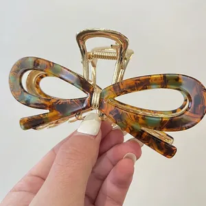 Détail d'une grande pince à cheveux nœud en acétate avec motif ambre et base dorée