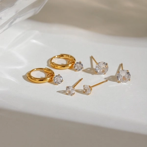 Détail de trois paires de boucles d'oreilles dorées avec zircons et anneaux simples