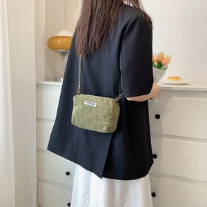 Close-up of olive green corduroy crossbody bag with golden chain and Fashion label