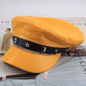 Detail of yellow PU leather flat cap with silver star studs and metal chain decoration