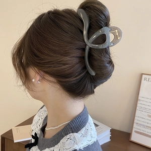 Elegant grey-blue acrylic hair claw clip in a sleek bow design on a female model