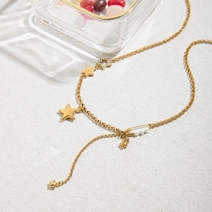Dettaglio della collana con ciondoli a stella dorati e spilla con perla fine