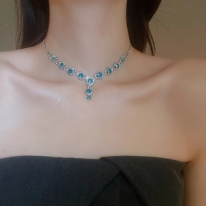 Close-up of elegant silver necklace set with blue gems and diamonds on model