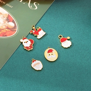 Detail view of five Christmas enamel charms including Santa and sleigh on green background
