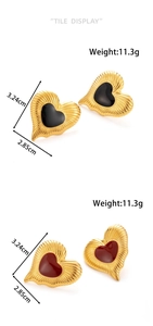 Detailed view of heart earrings with red and black enamel in hammered gold finish