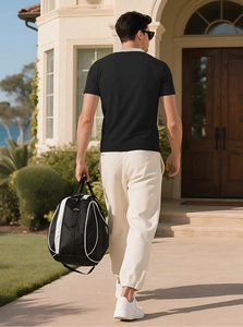 Homme portant un grand sac de sport noir et blanc dans un cadre extérieur ensoleillé