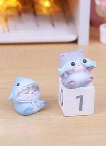 Cute resin shark cat and purple kitty ornaments displayed on a minimalist office desk
