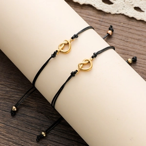 Detail of adjustable black woven knot bracelets with golden heart accents for couples