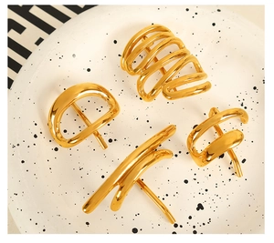 Detailed view of four gold-plated titanium steel hair pins on a beige ceramic plate