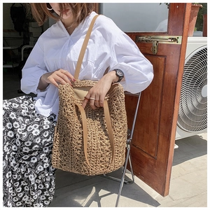 Close-up of woven hollow pattern straw tote bag with dual shoulder straps and top handles