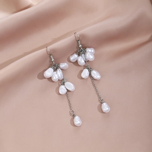 Detail of long fringe earrings with white pearls and silver chains on pink silk