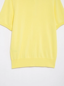 Detail of yellow knit polo top showing the ribbed cuff and hem texture with fine stitching