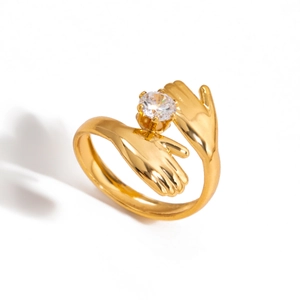 Detailed macro view of 18K gold plated hands holding a round zircon on a steel ring
