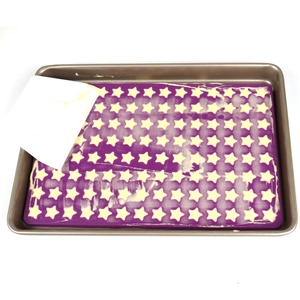 Detailed top view of purple batter being spread into a silicone mold with a white scraper