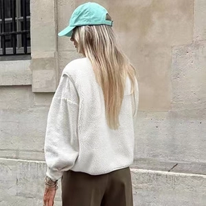 Outdoor back view of a white fleece vest paired with a mint green baseball cap