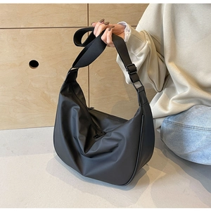 Detailed view of black nylon dumpling bag with adjustable strap in a lifestyle setting