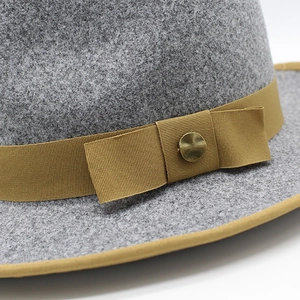 Macro detail of a grey wool fedora hat with a golden ribbed ribbon and metal buckle
