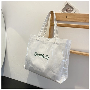Detail of transparent PVC layered white canvas tote bag with green Skillfully text