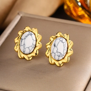 Macro shot of 18K gold-plated oval earrings featuring white stone with marble texture