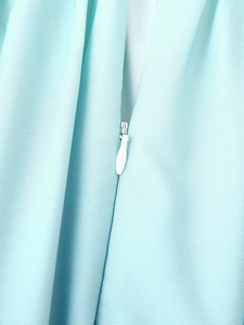 Vue macro d'une robe bleu clair avec une fermeture éclair invisible blanche en goutte d'eau